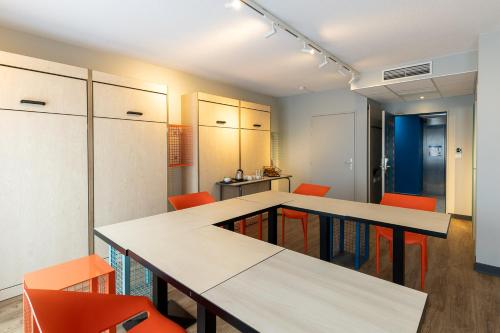 a room with two tables and orange chairs at ibis Budget Millau Viaduc in Millau
