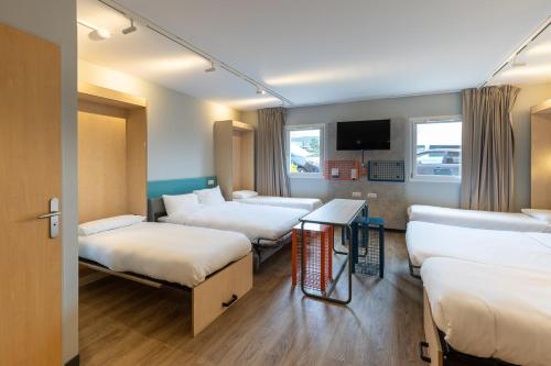 a room with three beds and a table in it at ibis Budget Millau Viaduc in Millau