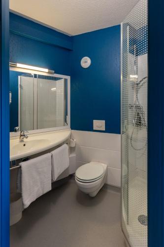 a bathroom with blue walls and a toilet and a shower at ibis Budget Millau Viaduc in Millau