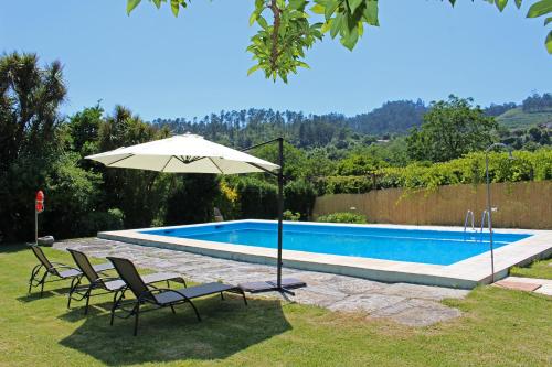 a swimming pool with two chairs and an umbrella at Recantos na Portela in Amares