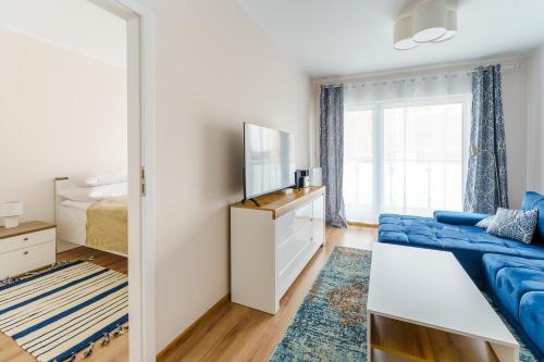 um quarto com um sofá azul e uma televisão em Apartamenty SUNSET RESORT SurfingBird Grzybowo em Grzybowo