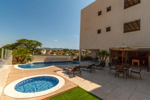 eine Terrasse mit einem Pool und Stühlen sowie ein Gebäude in der Unterkunft Ville de Montagne Hotel in Brumadinho