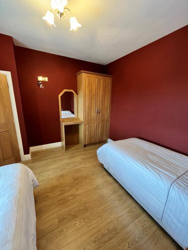a bedroom with red walls and a bed and a cabinet at Bridie's Place in Ballycastle