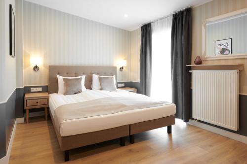 um quarto com uma cama grande com lençóis brancos e almofadas em AR Apartamenty em Poznań