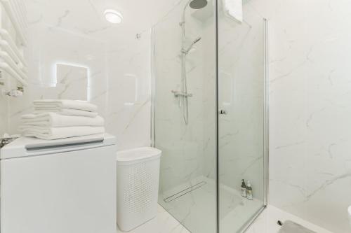 uma casa de banho com um chuveiro e uma porta de vidro em Apartamenty SUNSET RESORT SurfingBird Grzybowo em Grzybowo