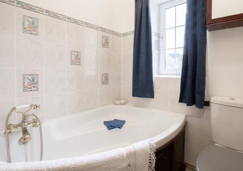 a white bath tub in a bathroom with a window at Buttercup Cottage in Tosside