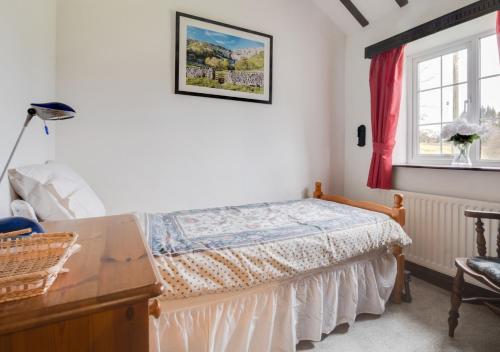 a bedroom with a bed and a desk and a window at Buttercup Cottage in Tosside