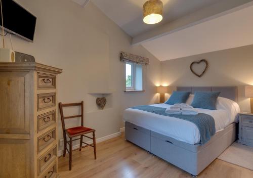 a bedroom with a bed and a dresser and a chair at Button Cottage in Bellerby