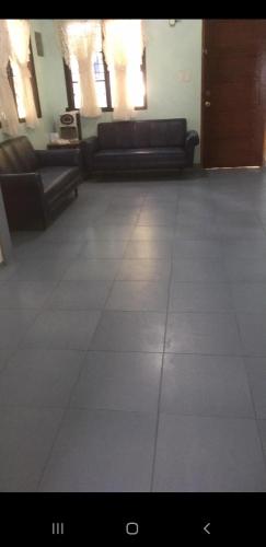 a living room with couches and a tile floor at Sandra's holiday house in Oslob