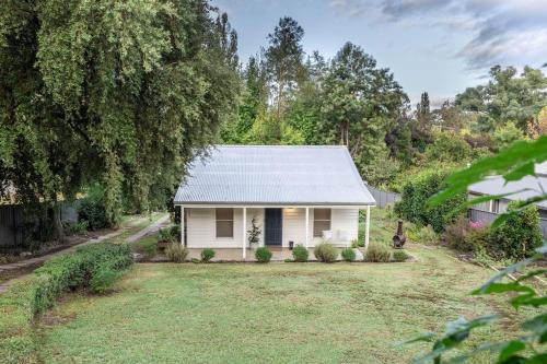 a white house with a grey tin roof at Myrtle Creek Cottage in Myrtleford