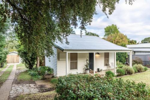 a small white house with a yard at Myrtle Creek Cottage in Myrtleford