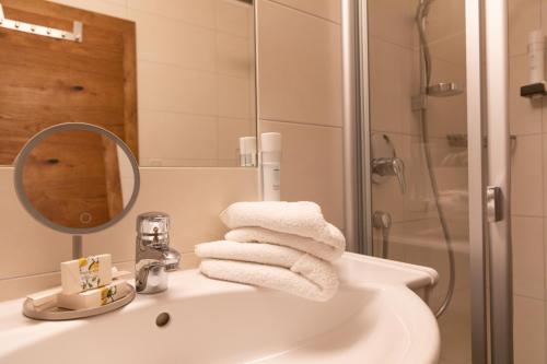 a bathroom with a sink with a shower and towels at Appartements Kirchenwirt in Kirchberg in Tirol