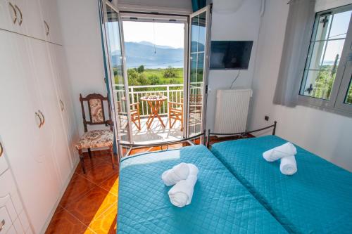 een slaapkamer met een blauw bed en een balkon bij SEA & OLIVES HOUSE in Lixouri