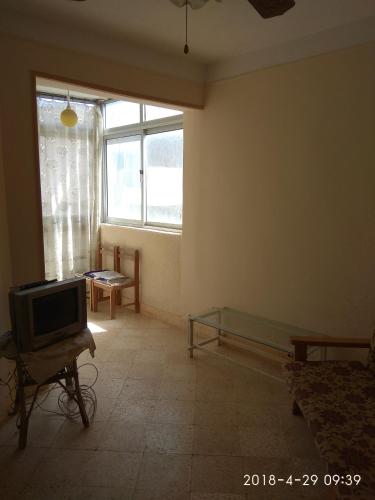 sala de estar con TV y ventana en شقه للايجار بيانكي السياحة البيطاش, en Alejandría