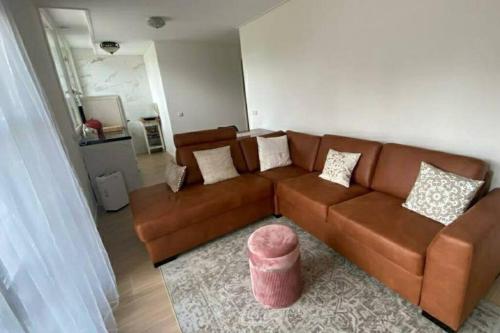 a living room with a brown couch and a pink stool at Landelijke huis in de Betuwe in Tricht