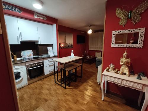 een keuken met rode muren en een kleine tafel in een kamer bij Apartahotel Rural CollaRubio Luxury in Collado Mediano
