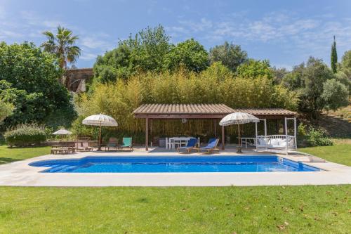 a pool with a gazebo with chairs and a table at Can Font de Muntanya Turisme Rural in Cruïlles