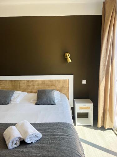 a bedroom with two beds and a black wall at Hotel La Potiniere in Hyères