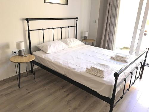 a bed with a black frame and white sheets and pillows at Pegasus Amazing Flat, 15min Walk To The Beach in Chania