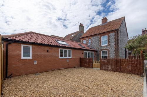 a brick house with a fence in front of it at The Ramey in Sheringham