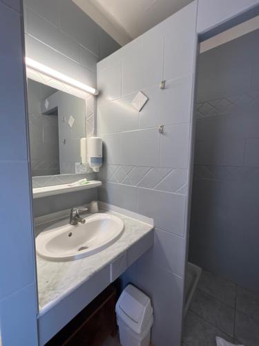 a white bathroom with a sink and a mirror at Hotel La Potiniere in Hyères