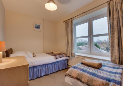 two beds in a room with a window at Blacksmiths Cottage in Catterick Bridge