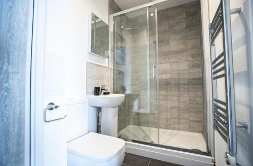 a bathroom with a shower and a toilet and a sink at Bayard Apartments - Duplex Penthouse Apartment in Peterborough