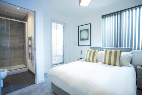 a bedroom with a large white bed and a bathroom at Bayard Apartments - Duplex Penthouse Apartment in Peterborough