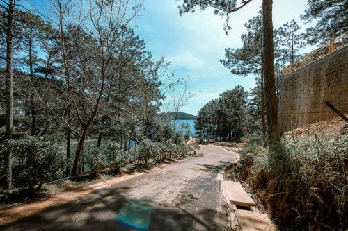 a dirt road with trees and a body of water at Dahlia Dalat in Xuan An