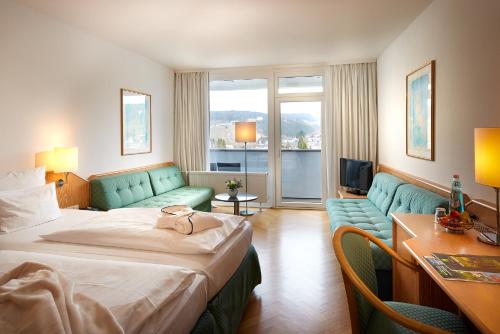 a hotel room with a bed and a couch at Sauerland Stern Hotel in Willingen