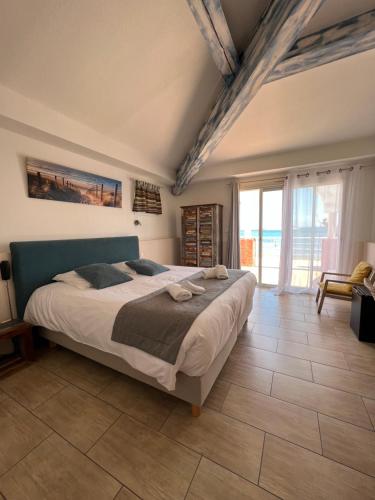 a bedroom with a large bed and a large window at Hotel La Potiniere in Hyères