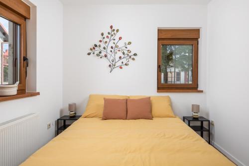 a bedroom with a bed with yellow sheets and two windows at Apartman Roko in Vrata