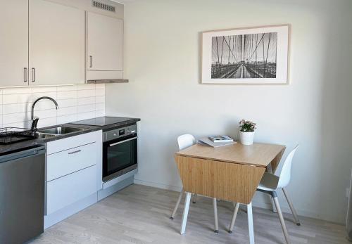 a kitchen with a wooden table and a sink at Hyllie Appartement - New Construction in Malmö