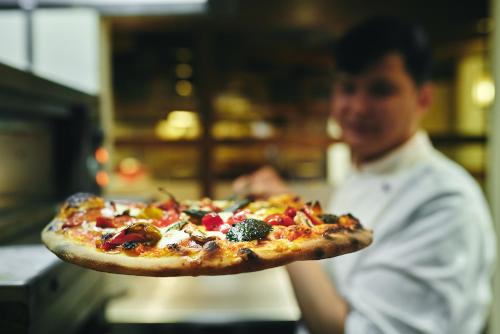 a person holding a pizza on a tray at Sauerland Stern Hotel in Willingen