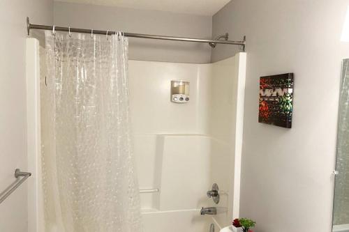 a white shower curtain in a bathroom with a tub at Exquisite Cozy Suite/full amenities in Kensington in Saskatoon