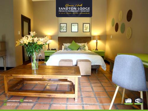 a bedroom with a bed and a table with a vase of flowers at Sandton Lodge Rivonia in Johannesburg