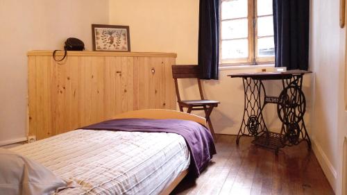 Schlafzimmer mit einem Bett, einem Fenster und einem Tisch in der Unterkunft Le Gîte du Rocher - Auzat in Auzat