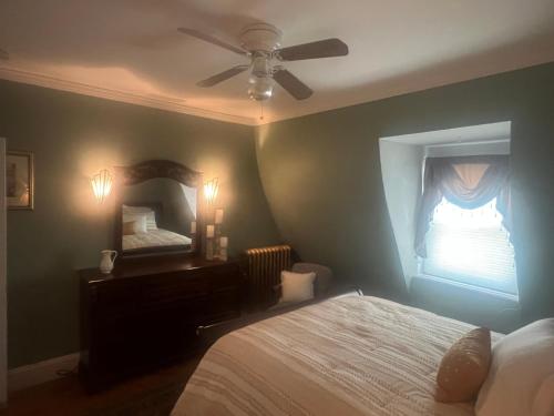 a bedroom with a bed with a ceiling fan and a mirror at Private Victorian Apartment in convenient City location on 5 acre, Sleeps 5 in Poughkeepsie