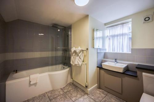 a bathroom with a bath tub and a sink at The White Hart Hotel in Uttoxeter