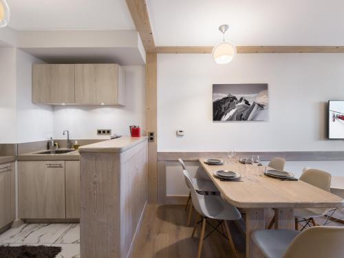 une cuisine et une salle à manger avec une table et des chaises dans l'établissement Appartement moderne au cœur de Courchevel Village, proche commerces et pistes, avec espace fitness. - FR-1-562-36, à Courchevel