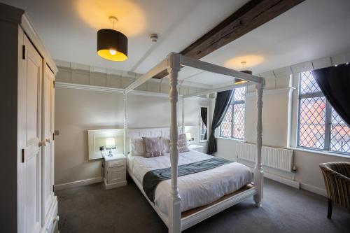 een slaapkamer met een hemelbed en ramen bij The White Hart Hotel in Uttoxeter
