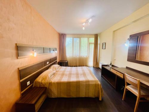 Habitación de hotel con cama y escritorio en Family Hotel Gorski Kut en Rilski Manastir
