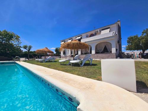 une villa avec une piscine en face d'une maison dans l'établissement CHALET ALICANTE Sol y Luz, à San Vicente del Raspeig