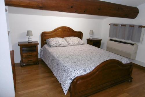 um quarto com uma grande cama de madeira e 2 mesas de cabeceira em Chambre d'hôtes + piscine em Cavaillon