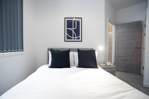 a white bed with black pillows in a bedroom at Bayard Apartments - Two Bedroom Apartment - Contractors Welcome in Peterborough