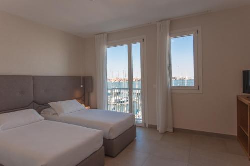 a hotel room with two beds and two windows at Mosella Suite Hotel in Sottomarina