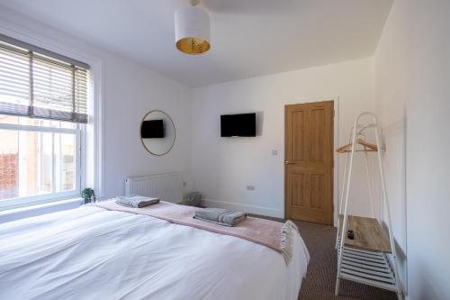 a white bedroom with a large bed and a window at The Ramey in Sheringham