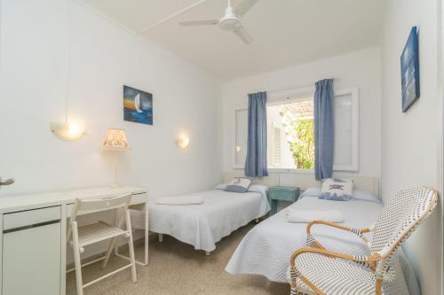 een witte kamer met 2 bedden, een bureau en een raam bij Villa Campins in Port d'Alcudia