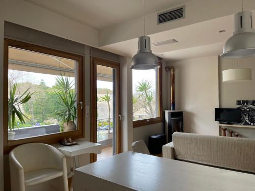 a living room with a table and chairs and windows at Oasis city apARTment in Heraklio