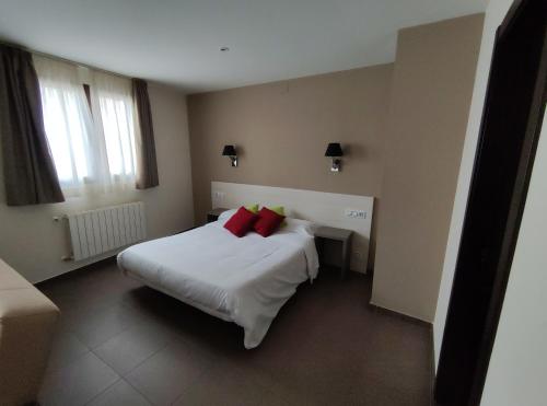 1 dormitorio con 1 cama blanca grande con almohadas rojas en Aparthotel Castellfort, en Castellfort